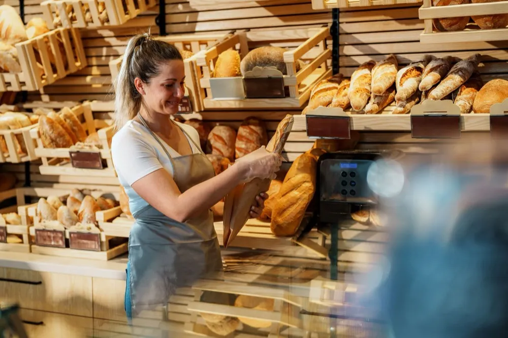 Baker arranging fresh breads on shelves